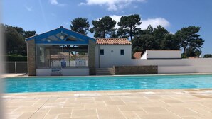 A swimming pool area with a lifeguard station, a small building, and a clear sky. - HOUSE WITH HEATED POOL CLOSE TO BEACHES AND NATIONAL FOREST (Saint-Jean-de-Monts, Vendée)