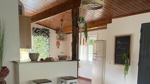 A spacious living area with a sofa, a kitchen with a bar, and a dining area. - DETACHED HOUSE IN THE CENTER OF VALE DAS FURNAS  (Furnas)