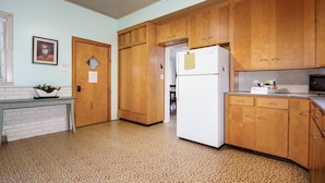 A kitchen with wooden cabinets, a white refrigerator, and a tiled floor. - Dog friendly one bedroom house close to everything! (Manistee)