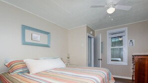 A bedroom with a bed, a ceiling fan, a framed picture on the wall, and a window. - Dog friendly one bedroom house close to everything! (Manistee)