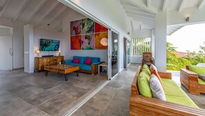 A spacious living area with a large flat-screen TV, a blue sofa, and a wooden coffee table. - Sugarbird Villa - Estate Coral (Rif. St. Marie)
