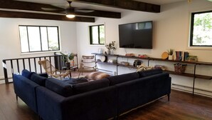 Una sala de estar moderna con un sofá modular, un ventilador de techo, un televisor de pantalla plana y una estantería.