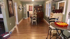 A spacious kitchen with wooden flooring, a dining table with chairs, and a fruit bowl. - Historic Downtown, Wifi, Apple TVs, Cold AC (Brownsville)