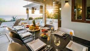 A dining area with a table set for four, overlooking a scenic view of the ocean. - Villa Vila Blenchi - Coral Estate (Rif. St. Marie)