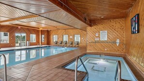 Una amplia piscina interior con paredes de madera, suelo de baldosas y vistas despejadas al exterior.