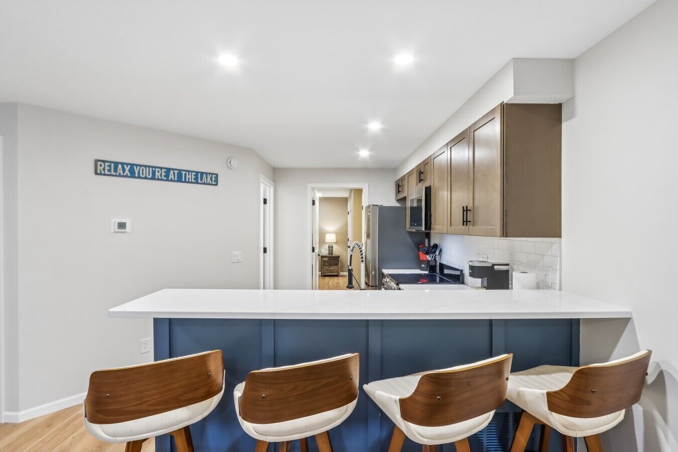 Une cuisine moderne dotée d’un îlot central, de tabourets de bar et de meubles de rangement en bois.