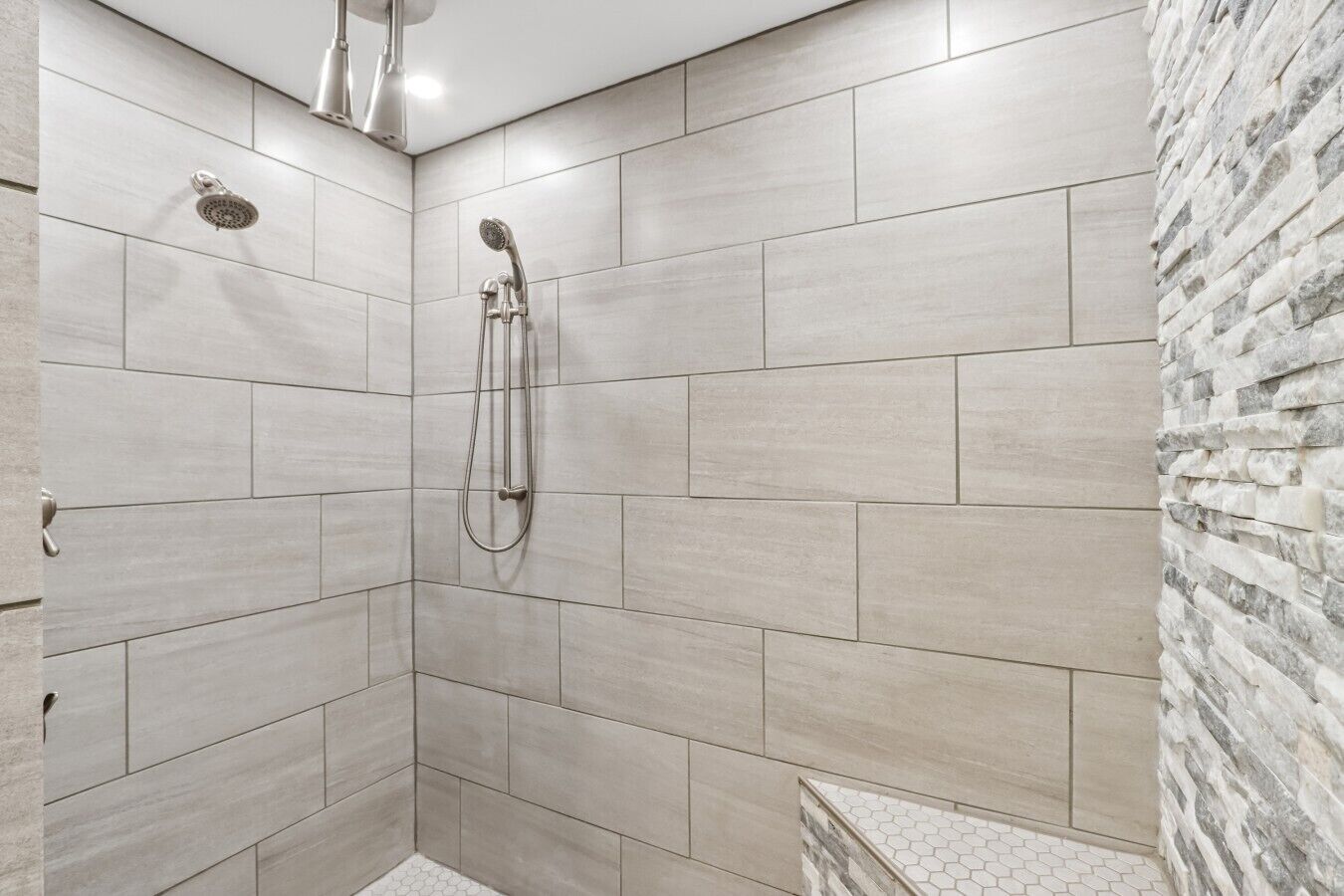 A shower with a handheld showerhead and a wall-mounted faucet.