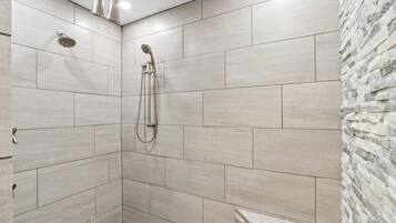 A shower with a handheld showerhead and a wall-mounted faucet.