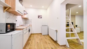 Eine kleine Küche mit weißen Schränken, einer Mikrowelle, einem Kühlschrank und einem Spülbecken.