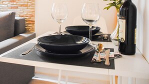 A dining table set with black plates, two wine glasses, cutlery, and a bottle of wine. - Cosy flat with balcony (Budapest)