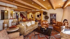 Ein geräumiges Wohnzimmer mit hohen Holzbalken, einem Sofa, einem Couchtisch und Ledersesseln.