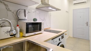 A modern kitchen with a microwave, kettle, and washing machine. - Cosy flat in Dob street, Juliet (Budapest)