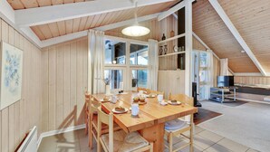 A cozy, wooden-paneled room with a dining table set for four, a television, and a large window providing natural light. - Amazing home in Hvide Sande with sauna (Hvide Sande)