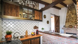 A kitchen with wooden cabinets, a tiled backsplash, a brick accent wall, and a stone accent wall. - Lovely home in Torrox with private swimming pool, can be inside or outside (Torrox)