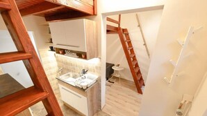Una cocina compacta con un lavamanos, una mesita y una escalera de madera que da a una zona superior.