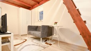 Una sala de estar moderna con un sofá gris, una mesita blanca y una escalera de madera.