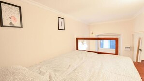 Un dormitorio con cama, un cuadro en la pared y una ventana con vistas al exterior.