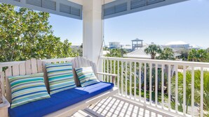 A covered outdoor seating area with a white railing, a blue cushioned bench, and striped pillows. - Gulf View - 30A Private Heated Pool, 3 min walk to the beach. No roads to cross. (Santa Rosa Beach)