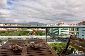 Un balcon avec une table en bois, deux bols remplis de collations et un verre d’eau.