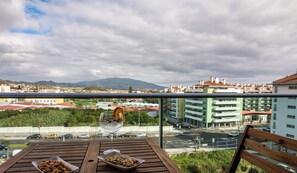 A balcony with a wooden table, two bowls of snacks, and a glass of water. - Home Azores - Mountain View Apartment (Ponta Delgada)