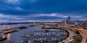A marina with boats docked, a cityscape with buildings, and a clear sky. - Home Azores - Mountain View Apartment (Ponta Delgada)