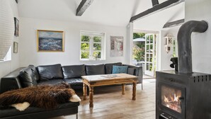 Uma sala de estar aconchegante com um sofá de couro preto, uma mesa de centro de madeira e uma lareira.