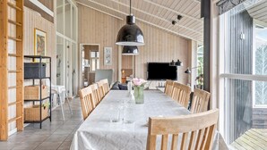 Un comedor amplio con una mesa larga, sillas de madera y una lámpara colgante grande.