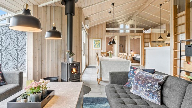 Una sala de estar acogedora con chimenea, paredes de madera y un sofá con cojines decorativos.