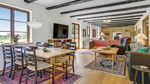 Un grand salon comprenant une table à manger, des chaises, un téléviseur et une cheminée.