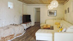 Una sala de estar con un sofá blanco, un televisor y una mesa de centro de madera.