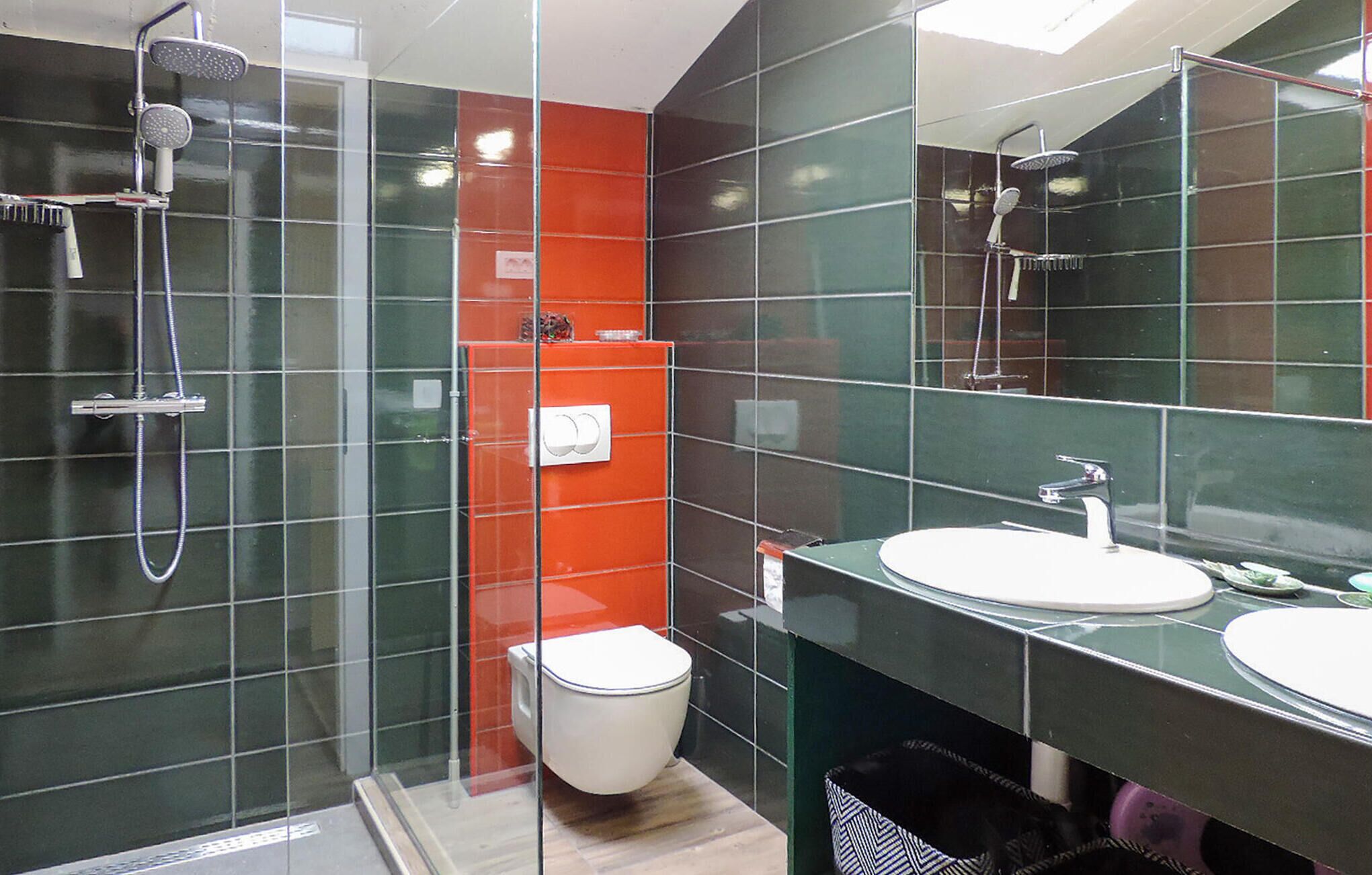 A modern bathroom with a glass shower enclosure, a white toilet, and a sink with a mirror.