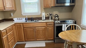 A kitchen with wooden cabinets, a stainless steel microwave, a stove, and a dining table.