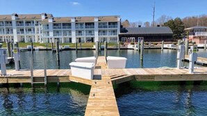 A marina with wooden docks and a building with multiple balconies in the background. - Waterfront Setting w/ Top-Floor Views Overlooking Lake Charlevoix (Charlevoix)