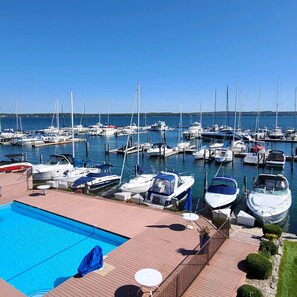 A marina with boats docked, a swimming pool, and a wooden deck with seating.