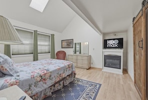 Un dormitorio con cama, cómoda, espejo, chimenea y un cartel de HBO Max.
