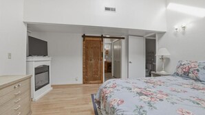 Une chambre à coucher avec un lit, une commode, un téléviseur et une porte en bois.