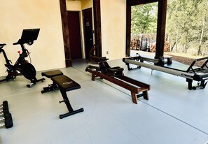 A gym with exercise equipment including a treadmill, stationary bike, and benches.