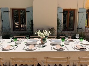 A table set for a meal with a vase of flowers, green glassware, and white plates. - Wine country Estate, Heated Pool, private vineyard and Olive Farm (Glen Ellen)