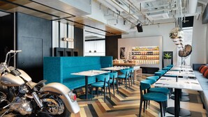 A modern restaurant with a long counter, blue chairs, and a motorcycle parked outside.