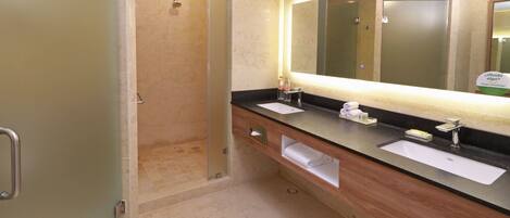 A modern bathroom with a glass-enclosed shower, two sinks, and a large mirror with integrated lighting.