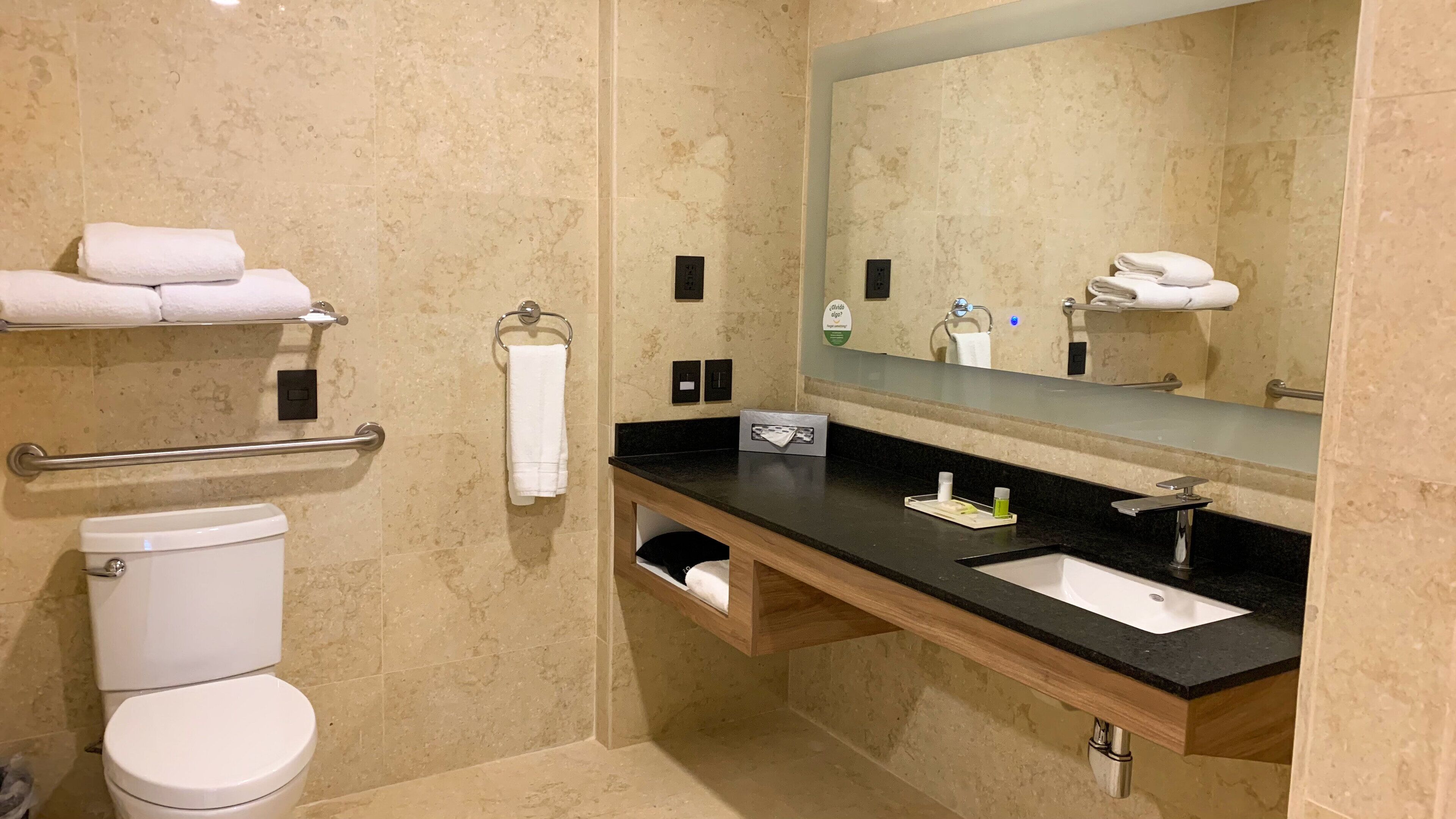Ein Badezimmer mit Toilette, Waschbecken, Spiegel und Handtuchhalter.