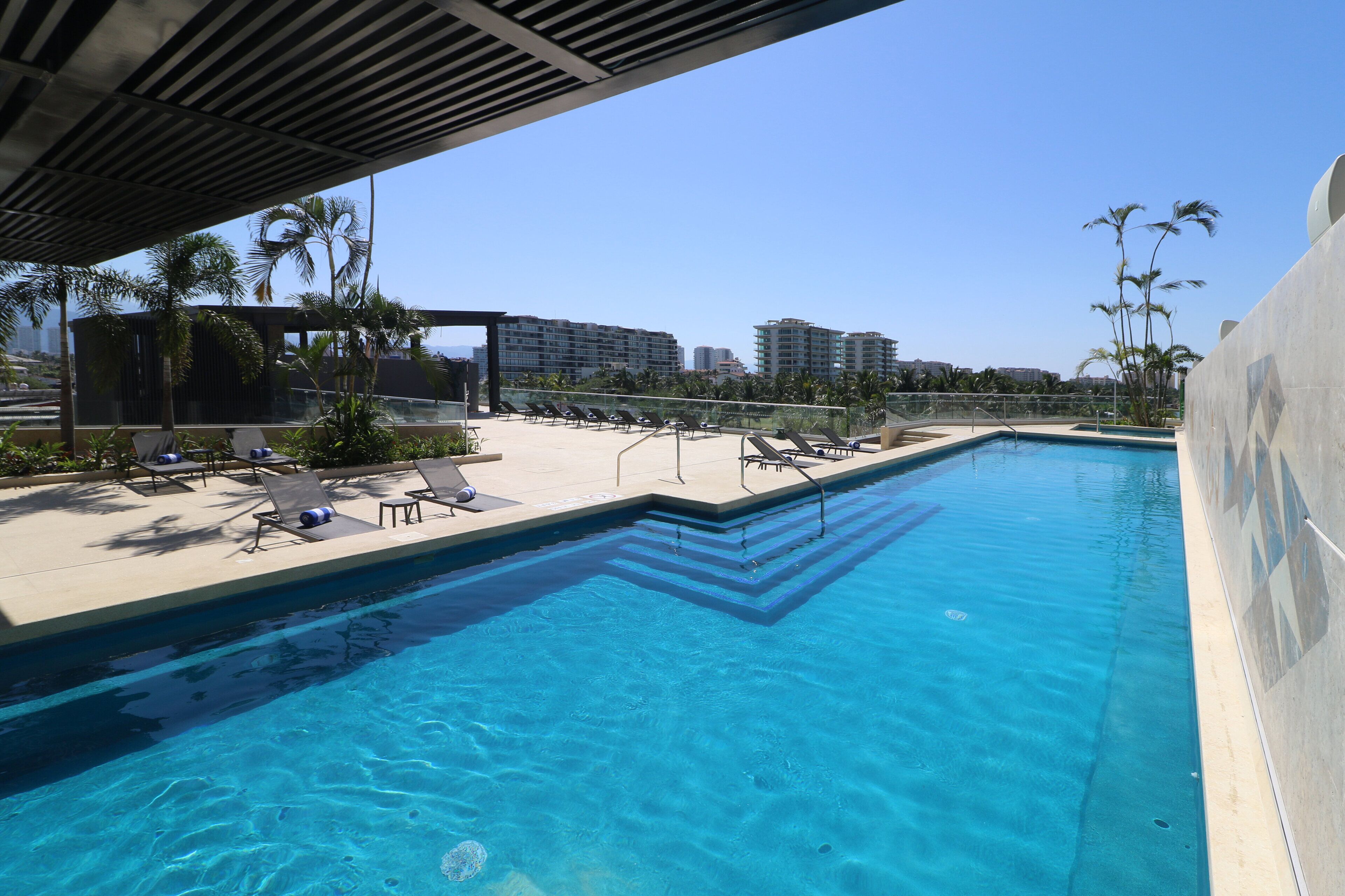 A swimming pool with lounge chairs and palm trees.
