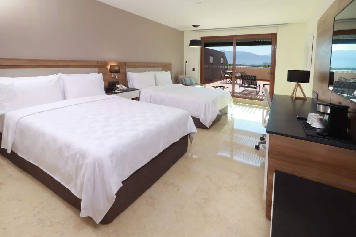 Une chambre d’hôtel avec deux lits, un bureau, une chaise et un balcon avec vue.