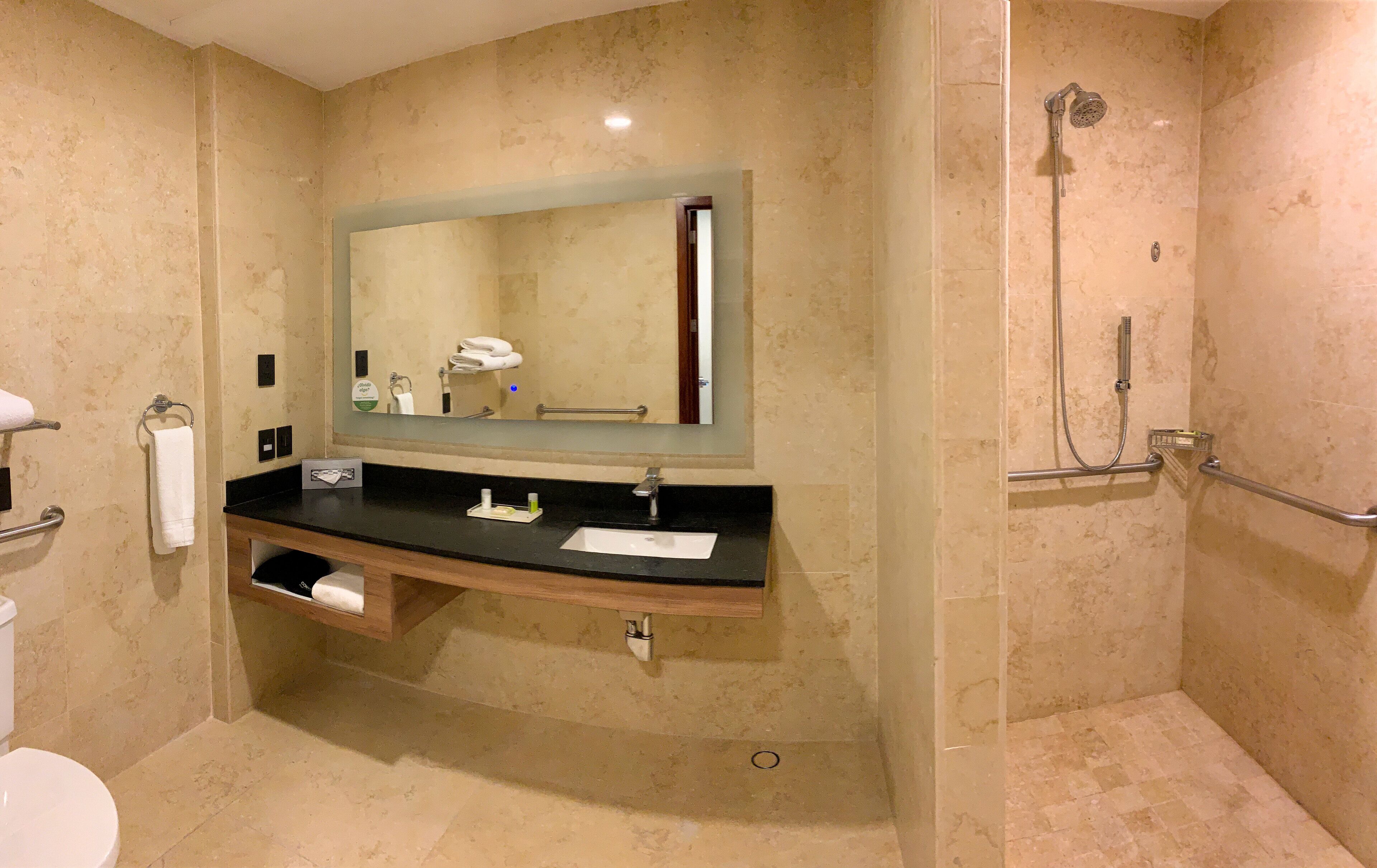 A bathroom with a sink, mirror, towel rack, and shower.