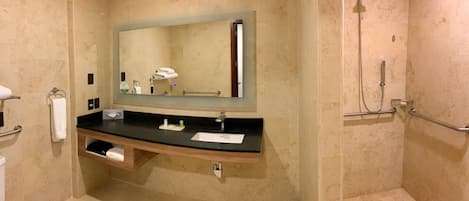 A bathroom with a sink, mirror, towel rack, and shower.