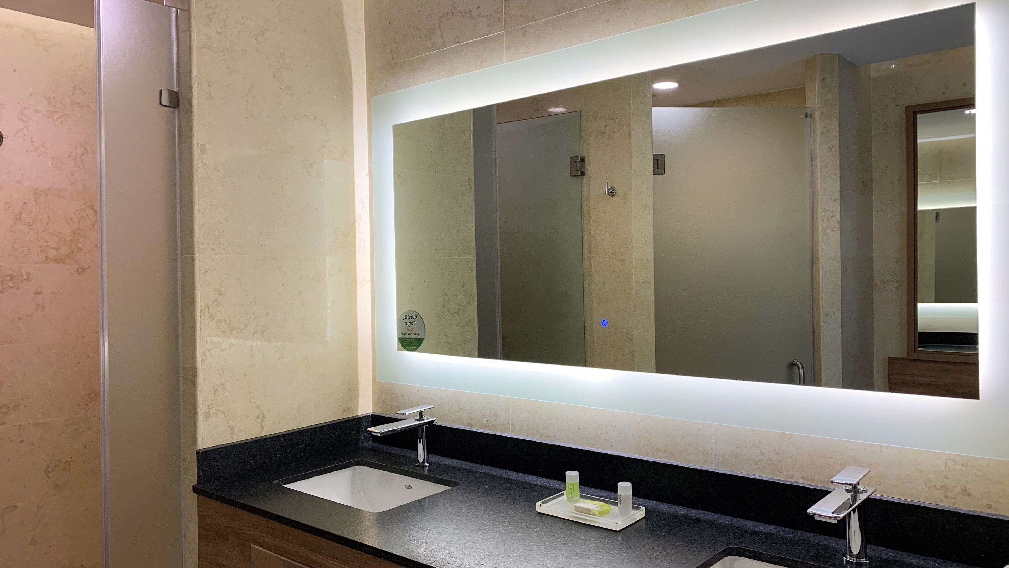 Un baño con dos lavamanos, un espejo grande y una zona de tocador iluminada.