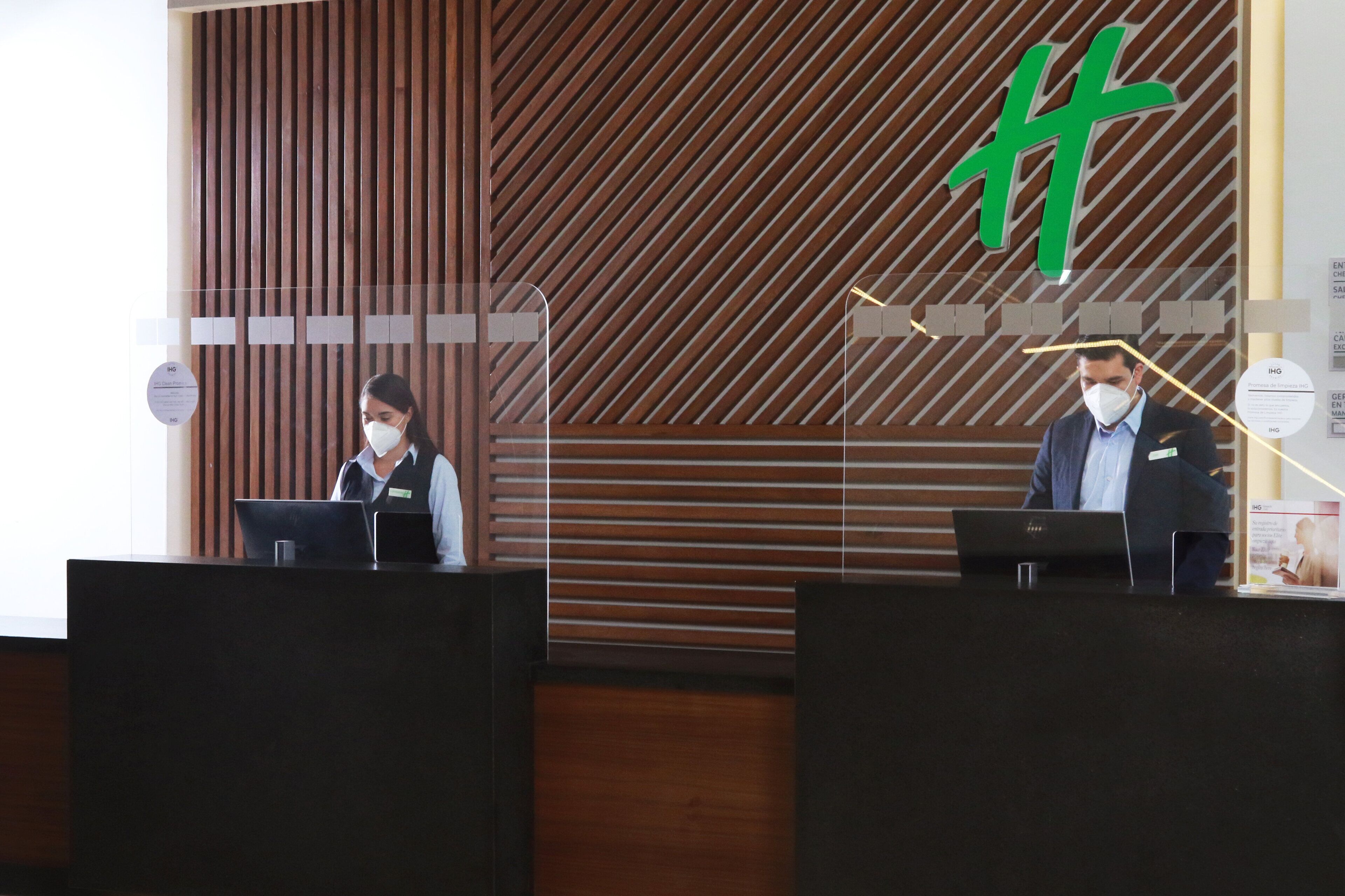 Un comptoir d’accueil avec un panneau arrière en bois et un logo vert.