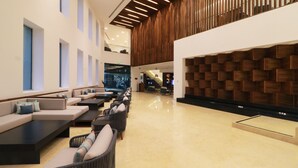 A modern lobby with a seating area, a wooden wall feature, and a staircase leading to an upper level.
