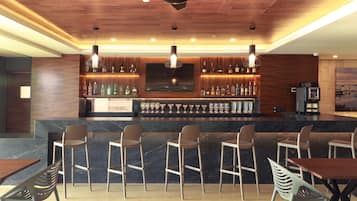 Una zona de bar con techo de madera, taburetes, un televisor en la pared y una máquina de café.