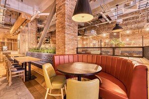 A modern interior with a brick wall, leather seating, and a round table. - Premier Inn Glasgow Cc St Enoch Square (Glasgow)